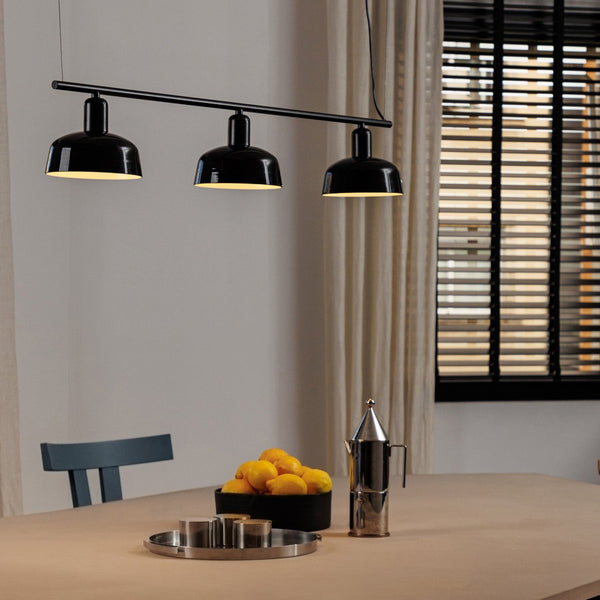 Modern black pendant light fixture over a dining table with decor items.