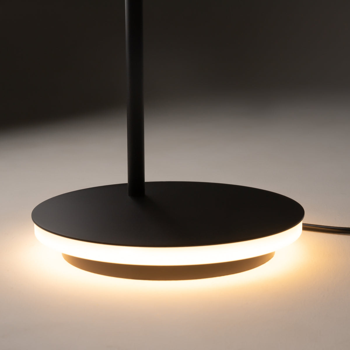 Modern black pendant light with a circular base on a dark background