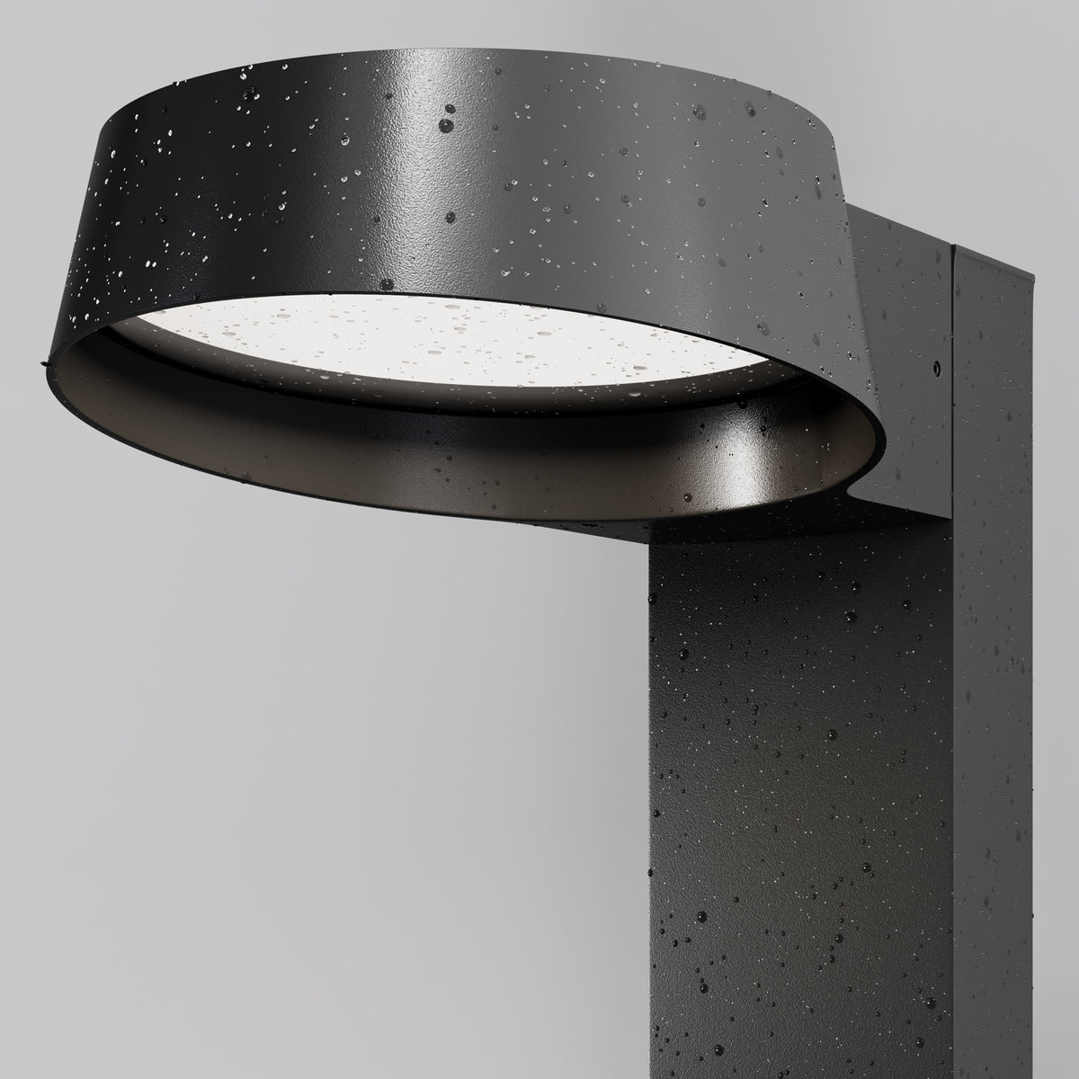 Close-up detail of the Share outdoor LED bollard light showing graphite powder-coated aluminum head, water droplets, and downward glass diffuser
