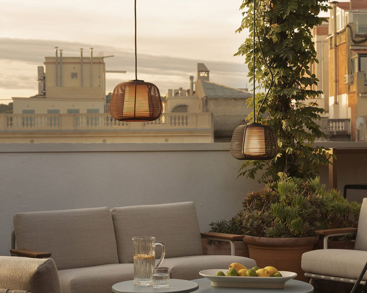 Modern black spherical outdoor pendant lights hanging in a lush garden with architectural landscape lighting at dusk