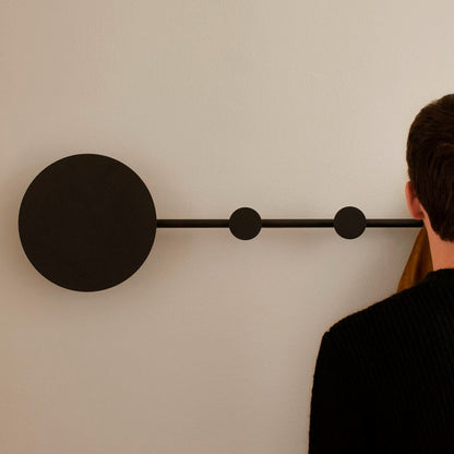 Person looking at a modern wall light fixture on a plain wall