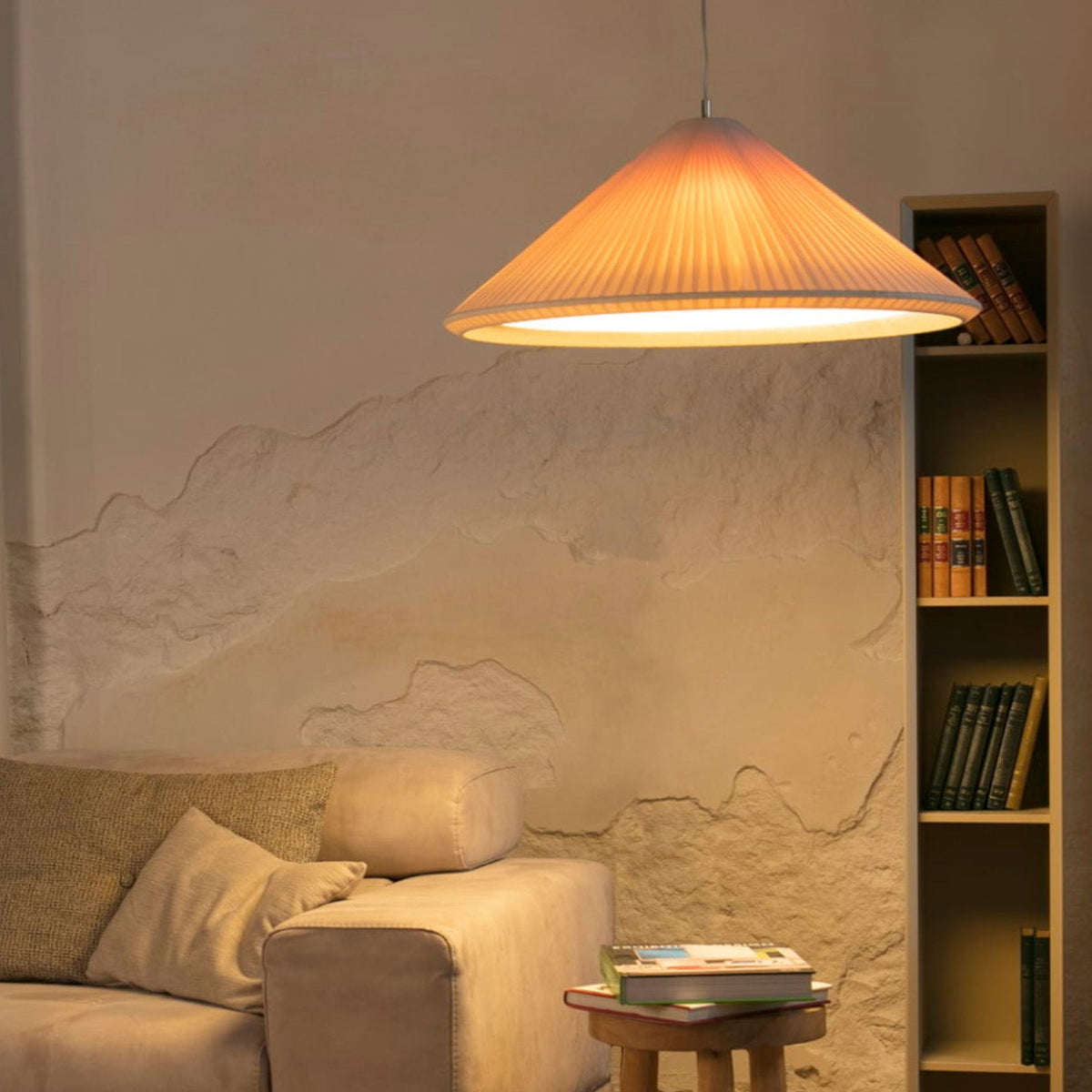 Living room with beige sofa, wooden coffee table, and bookshelf against a textured wall.