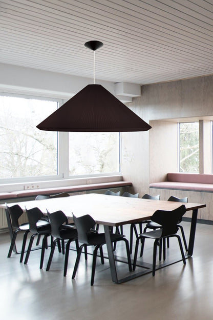 Modern interior with a black pendant light over a long white table with black chairs.