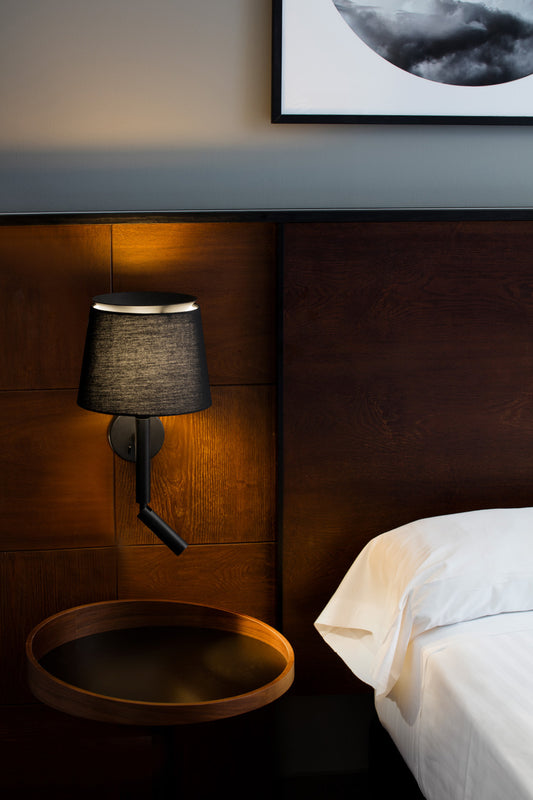 Bedroom setting with a wall-mounted lamp and wooden nightstand.