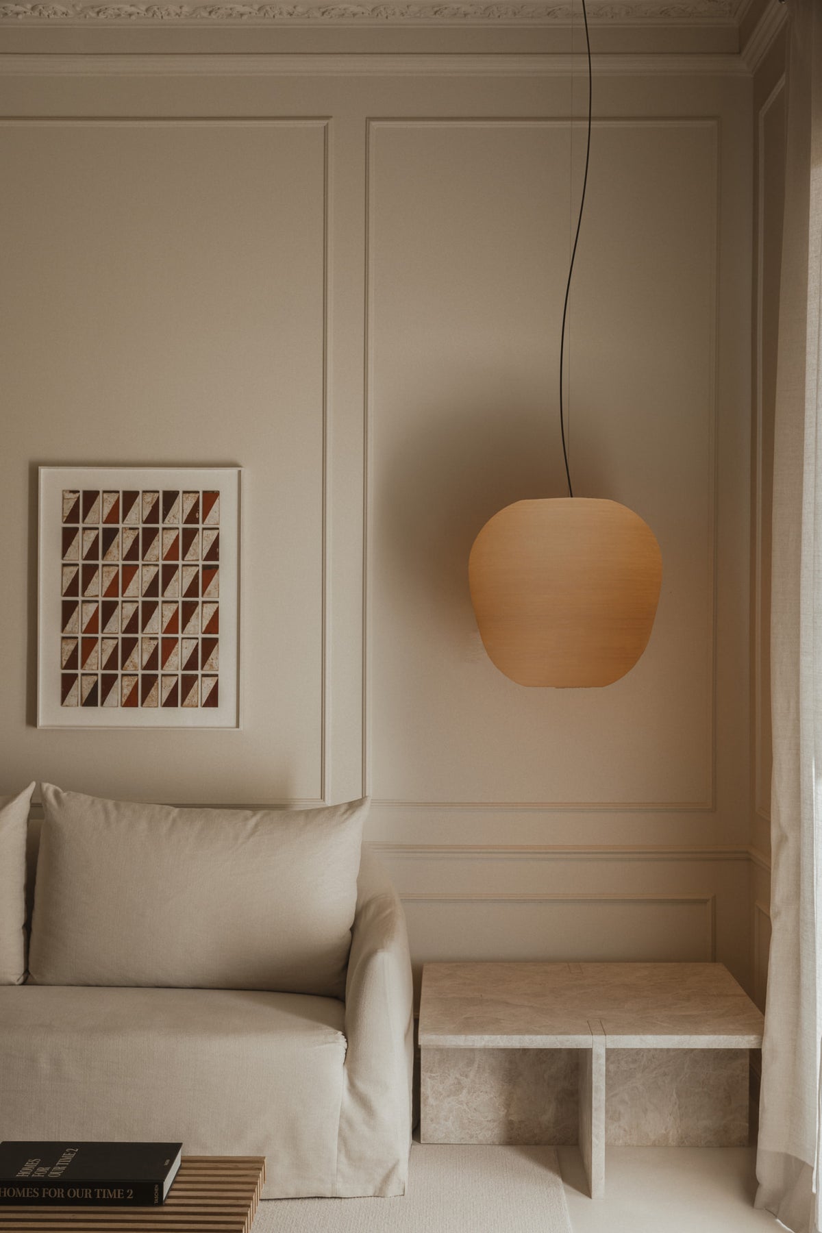 Modern interior with a beige sofa, pendant light, and wall art.