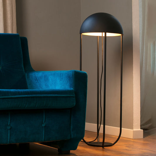 Modern floor lamp next to a blue sofa in a room with wooden flooring and neutral walls.