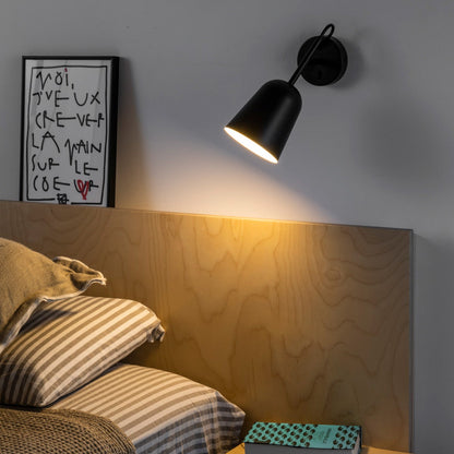 Modern bedroom with wooden headboard, black wall lamp, and framed artwork.