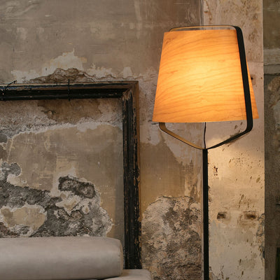 Floor lamp with a warm light in a room with textured walls and a sofa.