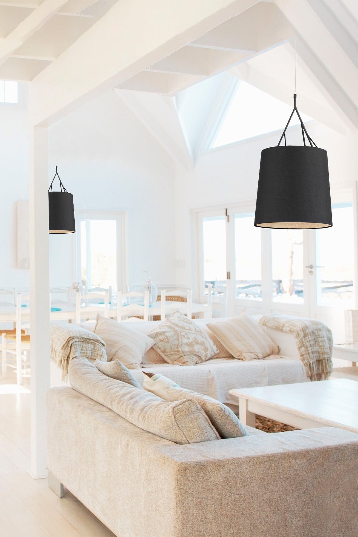 Modern living room with beige sofa, white walls, and black pendant lights.