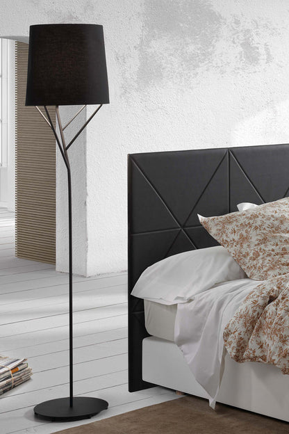 Modern bedroom with black geometric headboard, white bedding, and a black floor lamp.