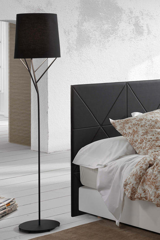 Modern bedroom with black geometric headboard, white bedding, and a black floor lamp.