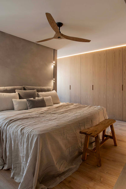 Modern bedroom with a bed, wooden bench, and ceiling fan.
