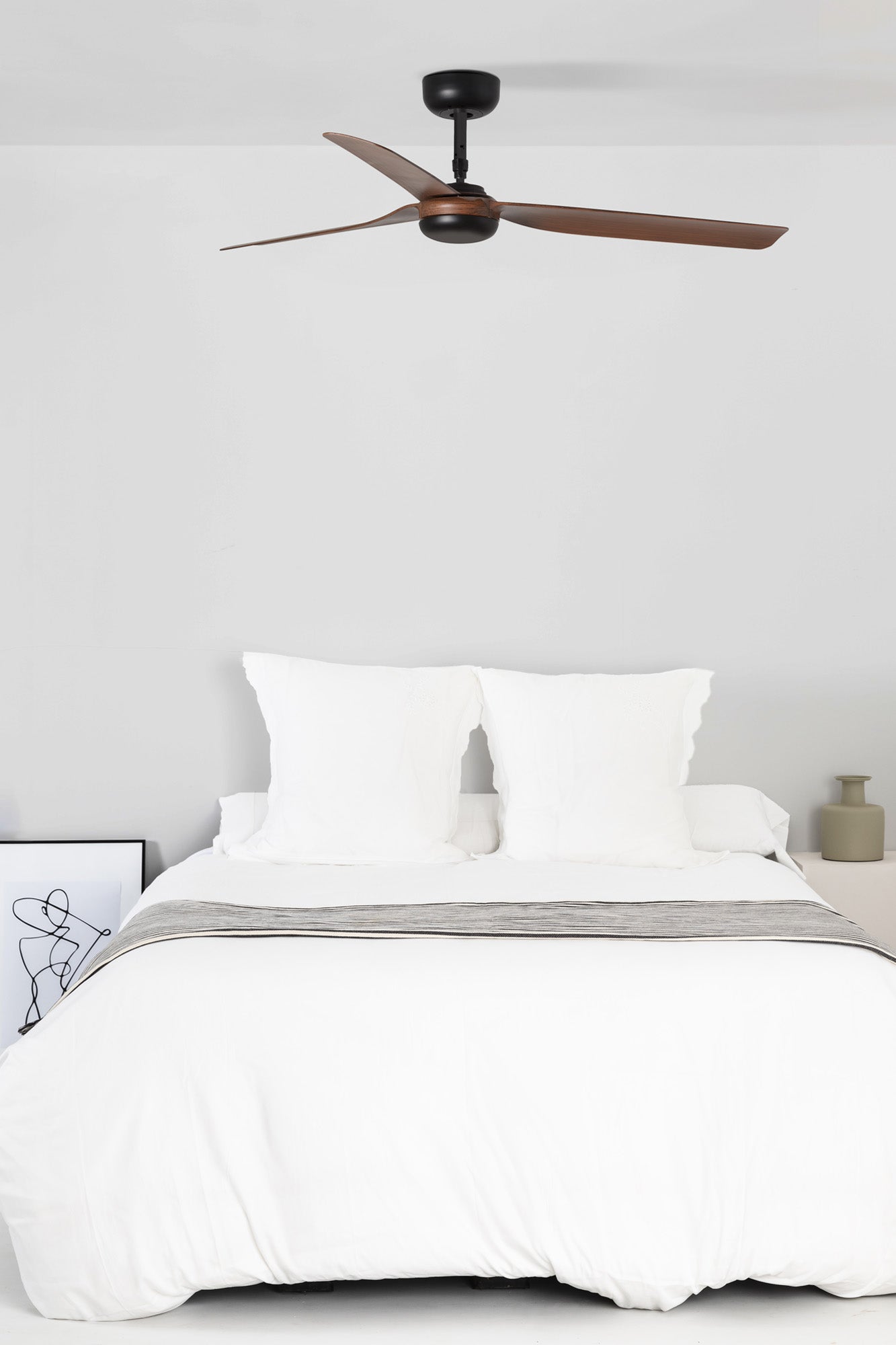 Bedroom with a ceiling fan above a neatly made bed.