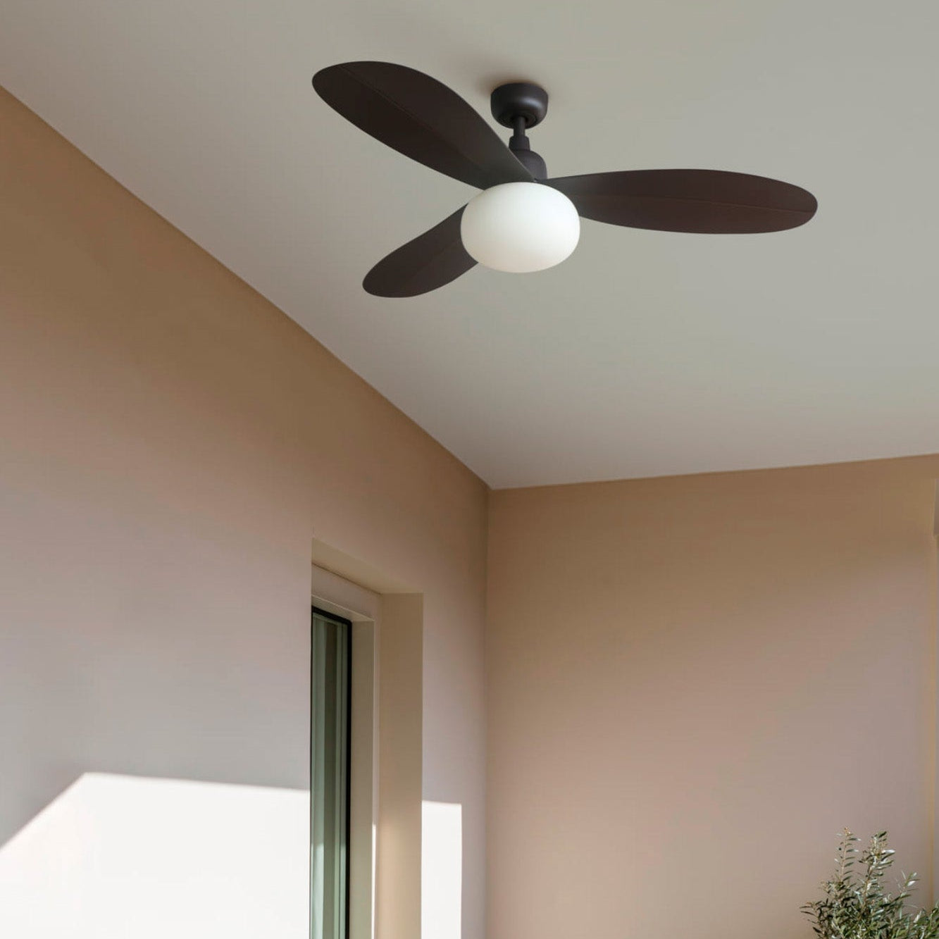 Ceiling fan in a room with light pink walls and a window.