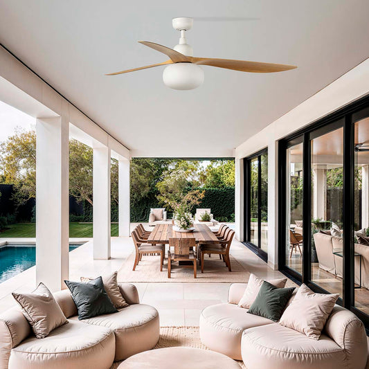 Modern outdoor living space with round beige sofa, cushions, and a ceiling fan.