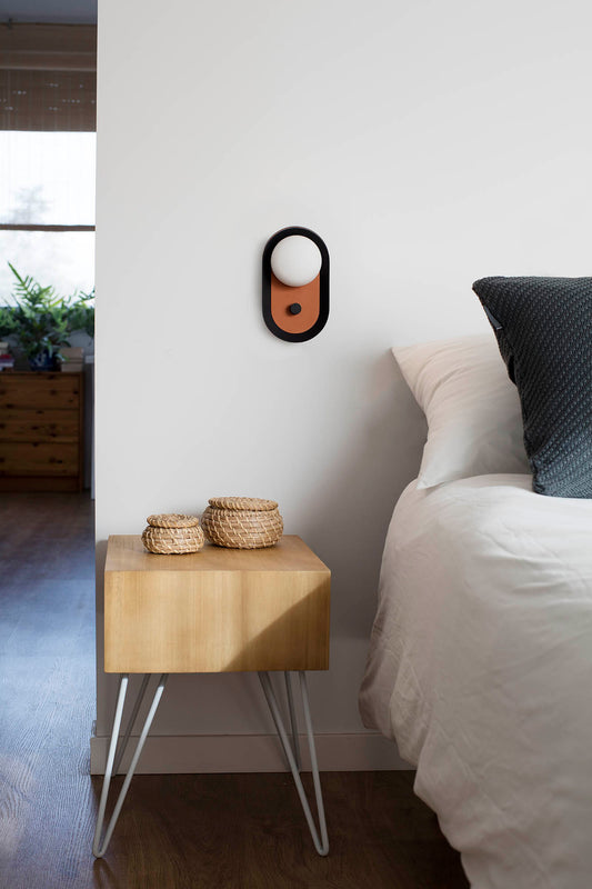 Wooden nightstand with woven baskets next to a bed with white bedding and a dark pillow.