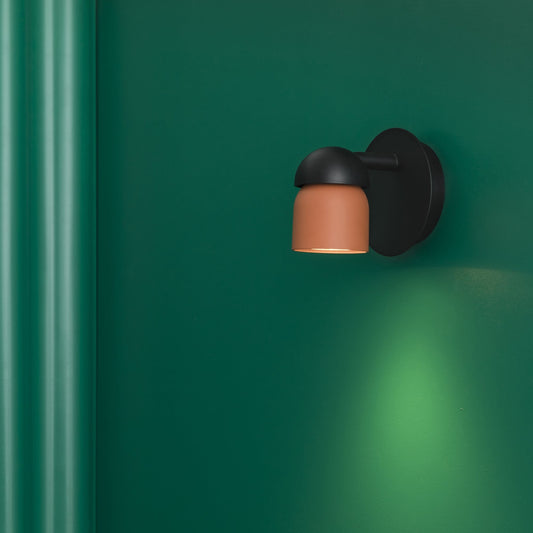 Black wall light fixture with a brown shade on a green wall