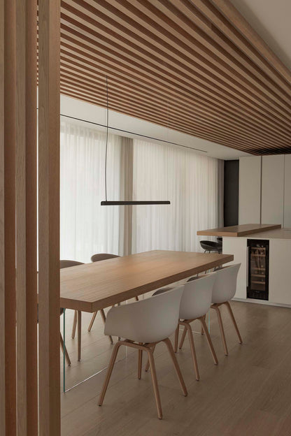 Modern dining area with wooden table and chairs in a well-lit room.