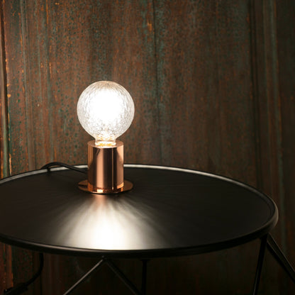 Light bulb on a metallic stand against a textured wall