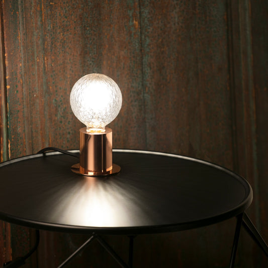 Light bulb on a metallic stand against a textured wall