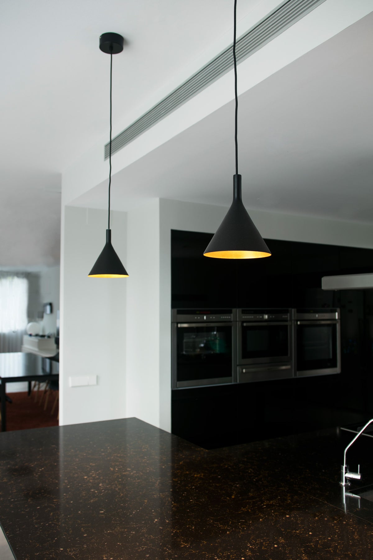 Modern kitchen with black pendant lights and a dark countertop.