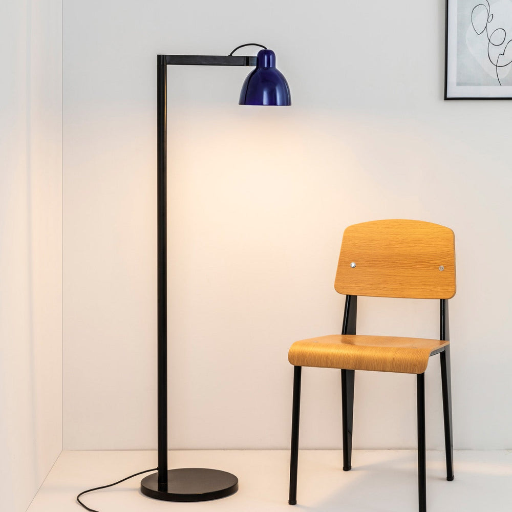 Yellow chair and black floor lamp against a white wall with a framed picture.