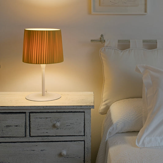 Bedroom scene with a lamp on a nightstand next to a bed.
