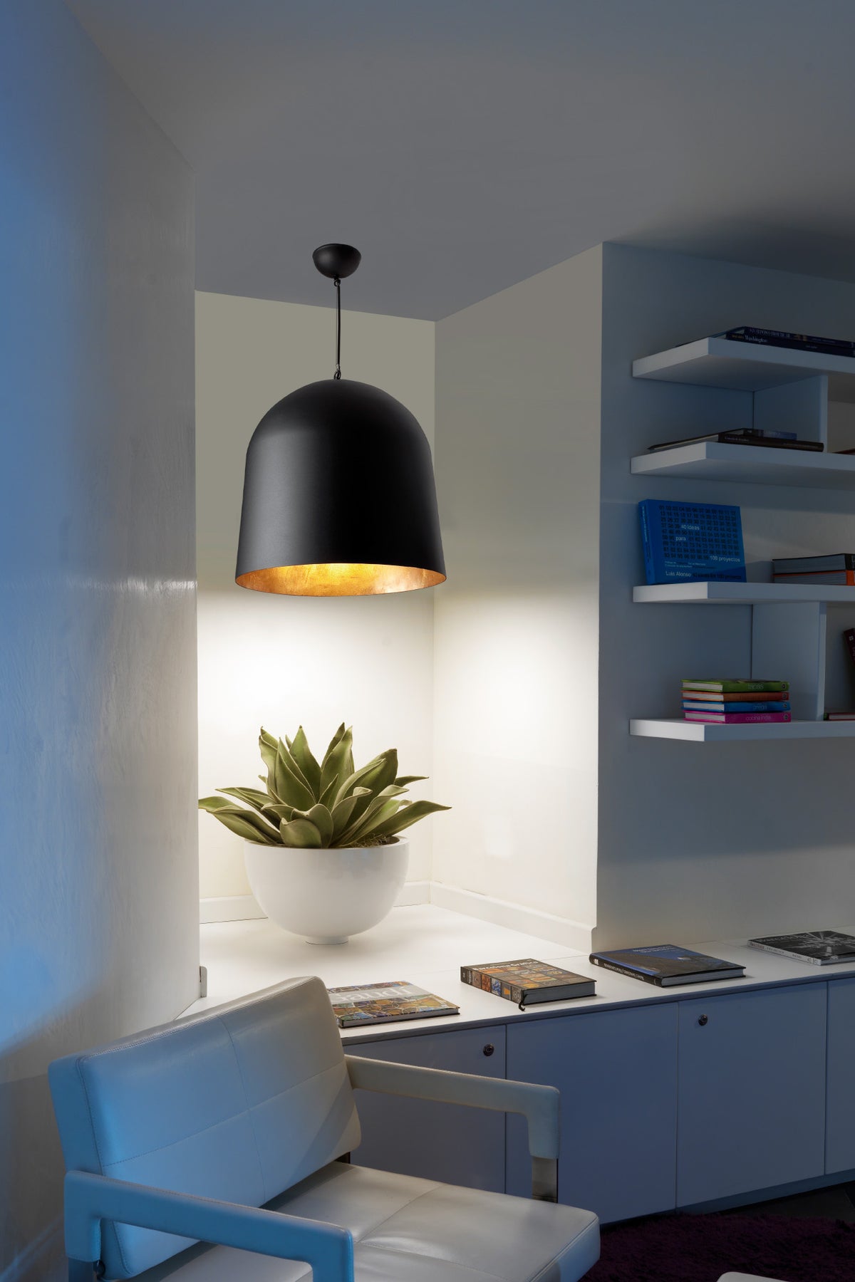 Modern interior with a black pendant light, white chair, and decorative items on shelves.