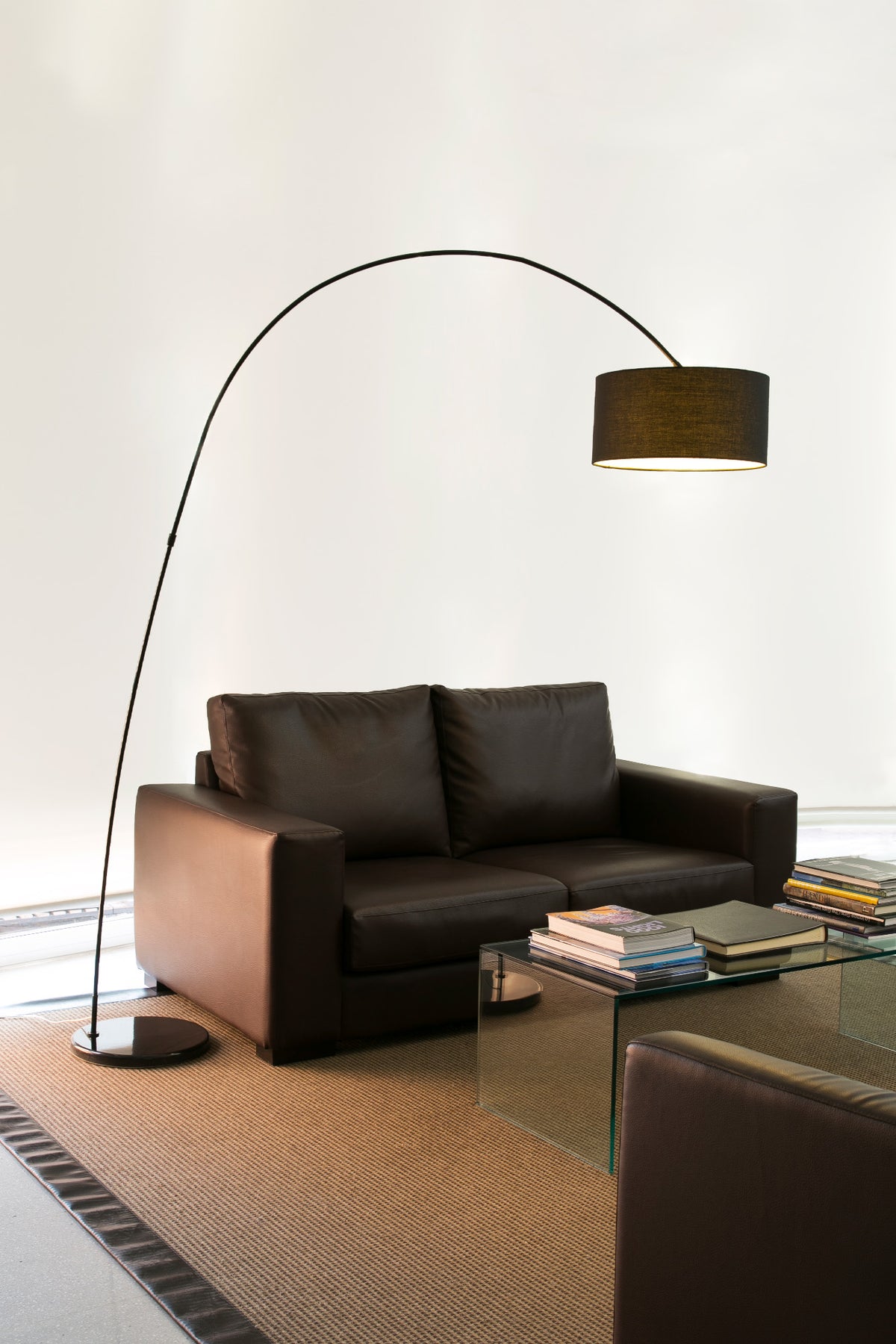 Modern living room with a brown leather sofa, glass coffee table, and a tall floor lamp.