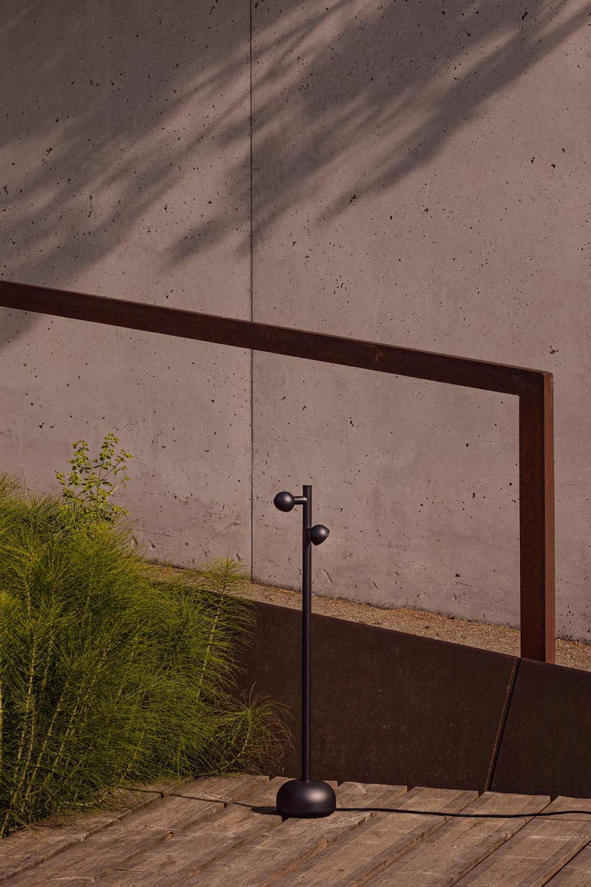 Modern outdoor lamp with a concrete wall and wooden floor in the background