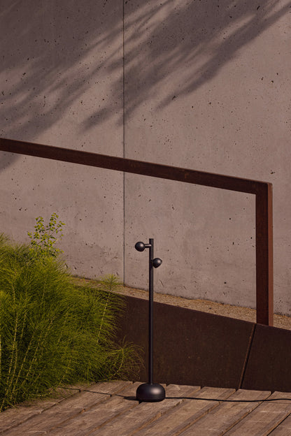 Modern outdoor lamp with a concrete wall and wooden floor in the background