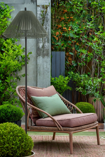 Wicker chair with cushions under a lamp in a garden setting