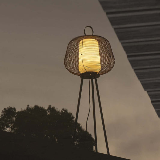 Outdoor lamp with woven shade and metallic base against a dark sky