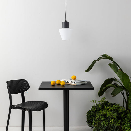 Black dining table with chair and fruit on a white floor with a plant