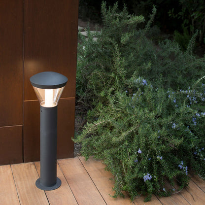 Outdoor garden light fixture on a wooden deck with greenery in the background