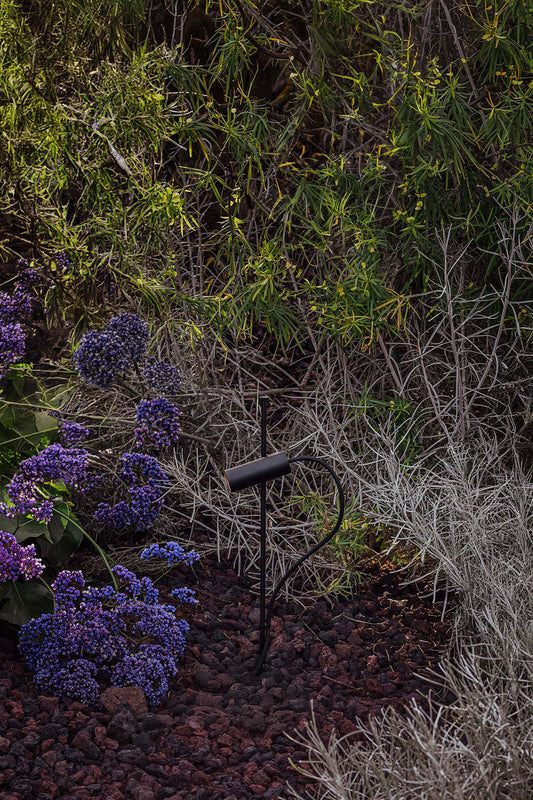 Decorative mailbox in a garden setting with purple flowers and greenery