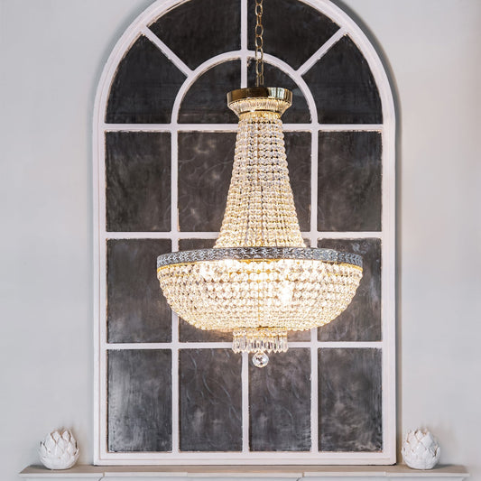 Crystal chandelier hanging above a fireplace with a decorative mirror in the background.