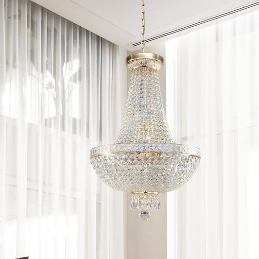 The Maytoni Bella gold classic chandelier suspended in a bright, elegant room with sheer white curtains, showcasing its cascading crystal beads and regal empire silhouette.