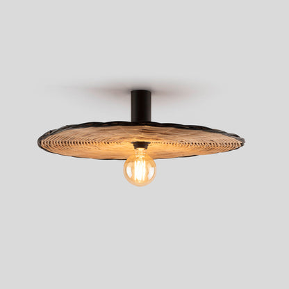 The Faro Barcelona Costas 600 lamp mounted as a flush ceiling light. It features a wide, woven natural rattan shade with a dark edge and a matte black cylindrical base, illuminating the space with an exposed decorative Edison-style bulb.