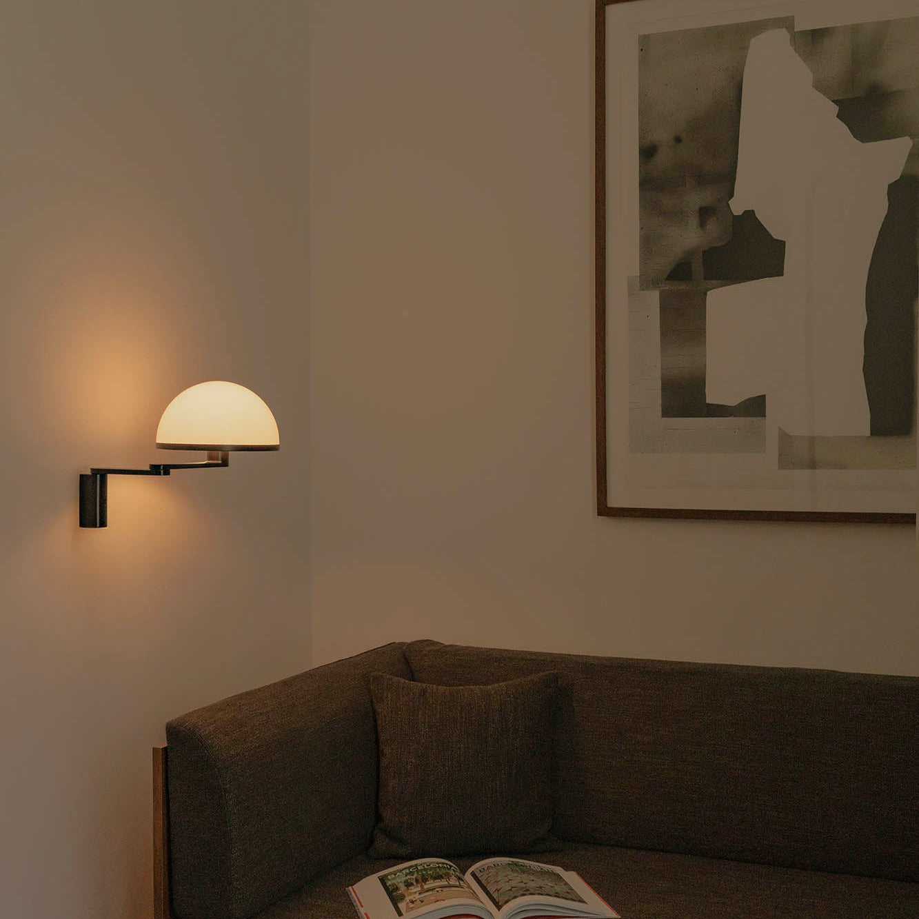 Dark-themed room with a sofa, lamp, and framed picture on a wall.