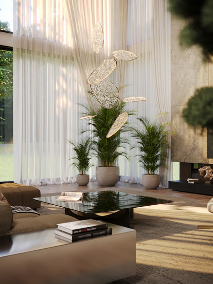 The Empire 110cm cascading LED chandelier suspended in a double-height modern living room with large sheer curtains and potted palms. Available to buy at the VXR Space store.