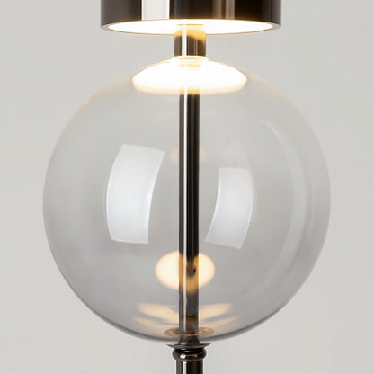 Modern lamp with a clear glass shade and metallic base on a light gray background