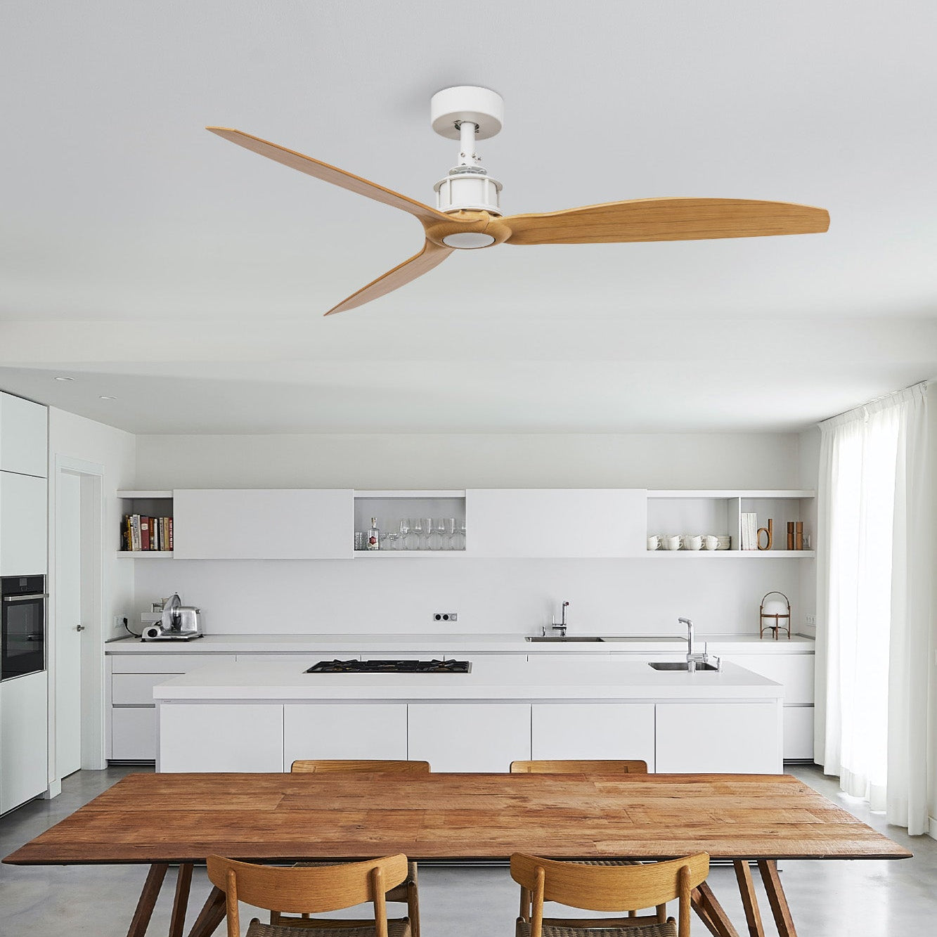 Modern kitchen with wooden dining table and chairs, ceiling fan, and white cabinetry.