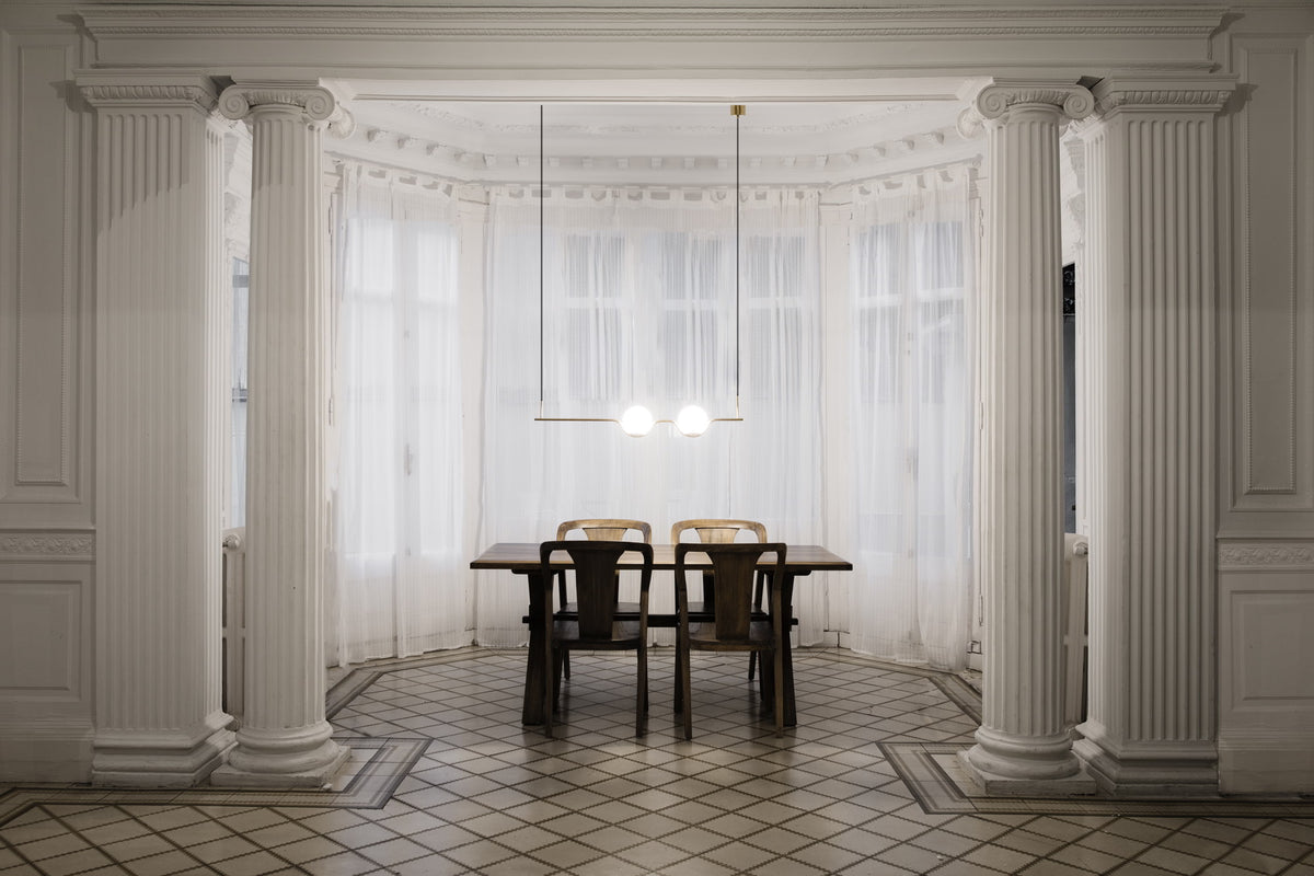 Dining area with classical columns and a table in a room with large windows.