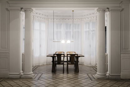 Dining area with classical columns and a table in a room with large windows.