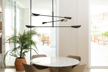 Modern dining room with a round marble table, chairs, and a stylish chandelier.