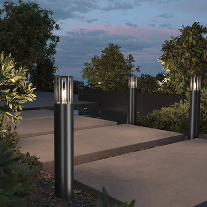 Outdoor garden pathway with cylindrical lamps illuminating the area.