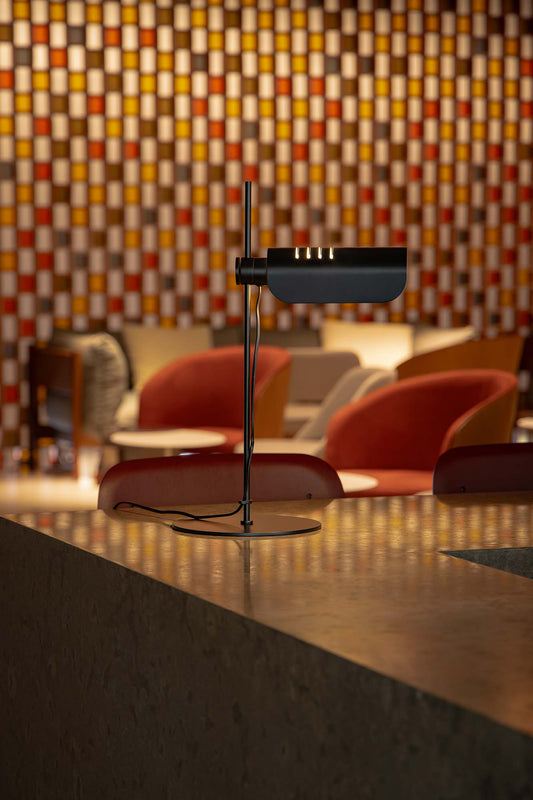 Modern black lamp on a reflective surface with a colorful geometric wall in the background