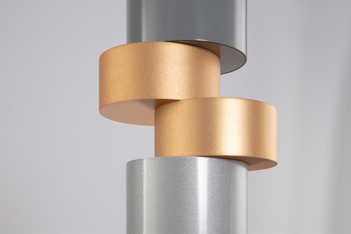 Close-up of a cylindrical metal object with gold and silver finishes on a light gray background
