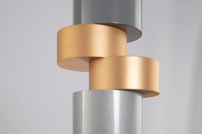 Close-up of a cylindrical metal object with gold and silver finishes on a light gray background